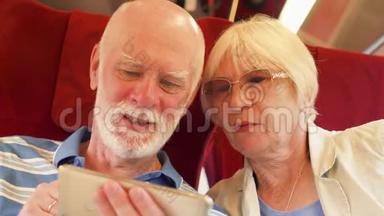 使用智能手机的高速国际列车的高级夫妇。 退休后积极的现代生活
